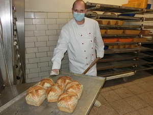 Auf dem Blech hat Alexander Koch, der eine starke Sehschwäche hat, frisch gebackenes Brot – die Heilwasserbrotsorte mit einer Krone.