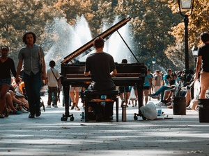 Ein Mann spielt im Washington Square Park in New York vor einer Fontäne Klavier.